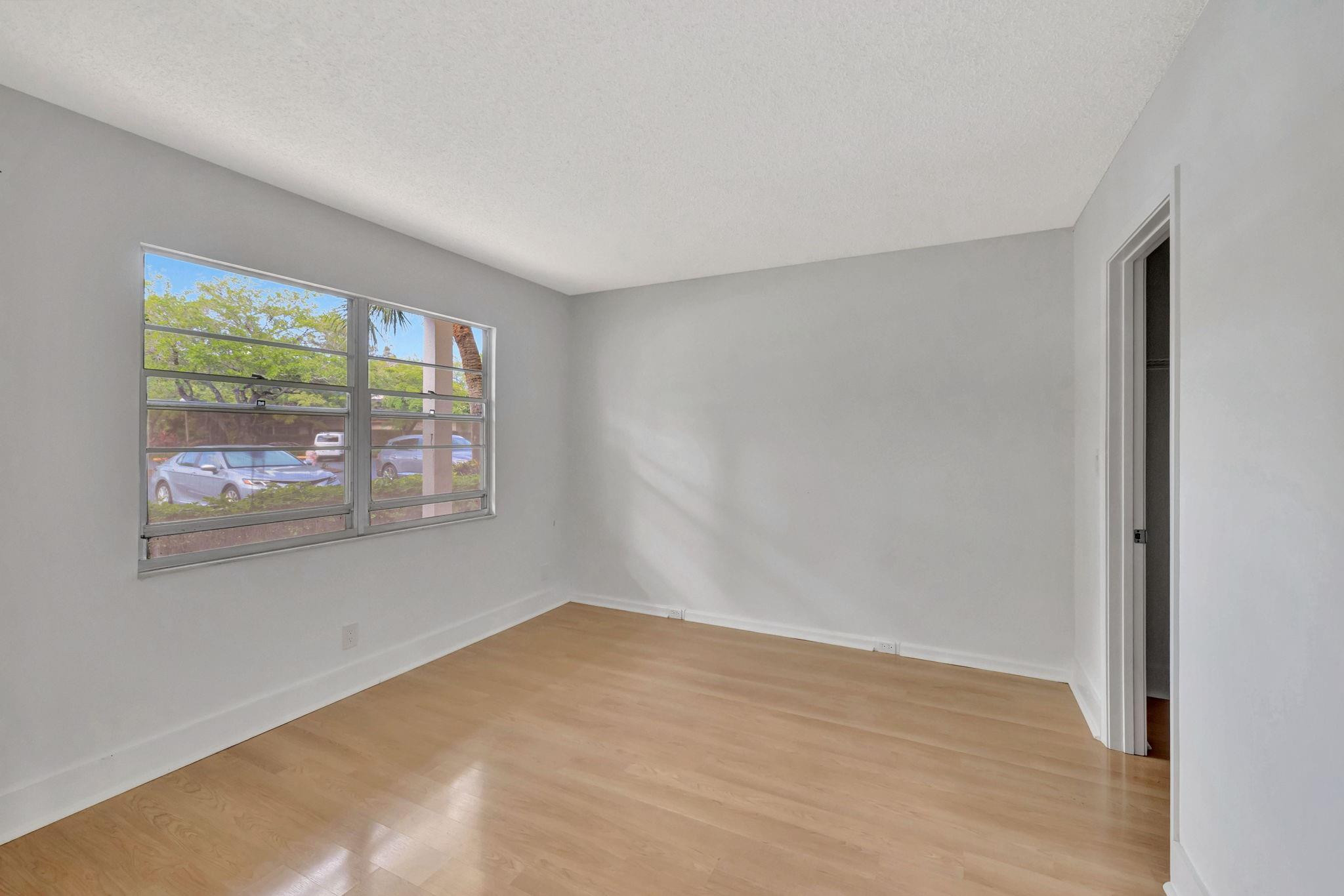 1801 Eleuthera Point, Unit E1 Coconut Creek, FL 33066 - Photo 25 of 50 a view of an empty room with wooden floor and a window