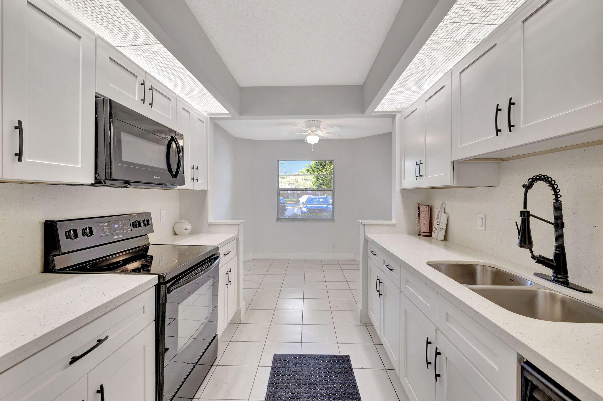 1801 Eleuthera Point, Unit E1 Coconut Creek, FL 33066 - Photo 6 of 50 a kitchen with granite countertop a sink a stove and cabinets