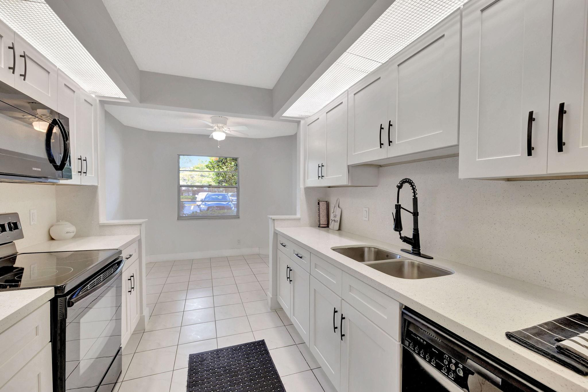 1801 Eleuthera Point, Unit E1 Coconut Creek, FL 33066 - Photo 8 of 50 a kitchen with a sink cabinets and appliances