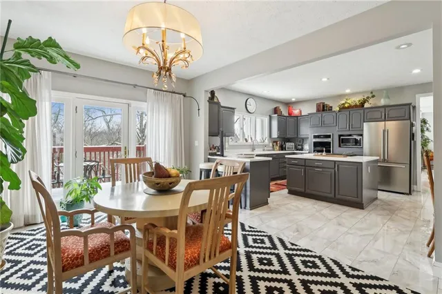 a kitchen with stainless steel appliances granite countertop a stove a sink dishwasher a dining table and chairs with wooden floor