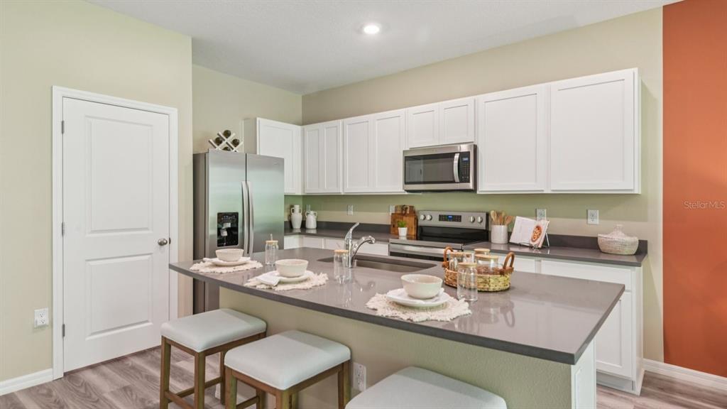 32467 Welling Blade Loop Wesley Chapel, FL 33545 - Photo 13 of 42 a kitchen with a sink a stove and chairs