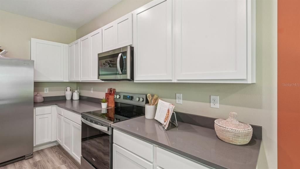 32467 Welling Blade Loop Wesley Chapel, FL 33545 - Photo 14 of 42 a kitchen with stainless steel appliances white cabinets sink and stove