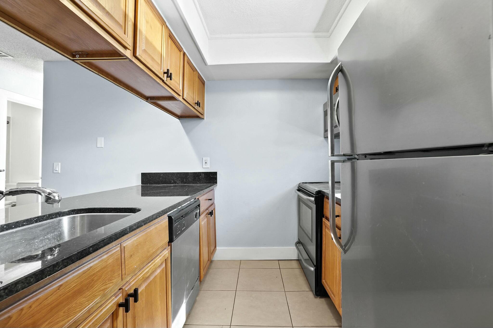 983 Northwest Spruce Ridge Drive, Unit 2 Stuart, FL 34994 - Photo 9 of 55 a kitchen with stainless steel appliances granite countertop a refrigerator and a sink
