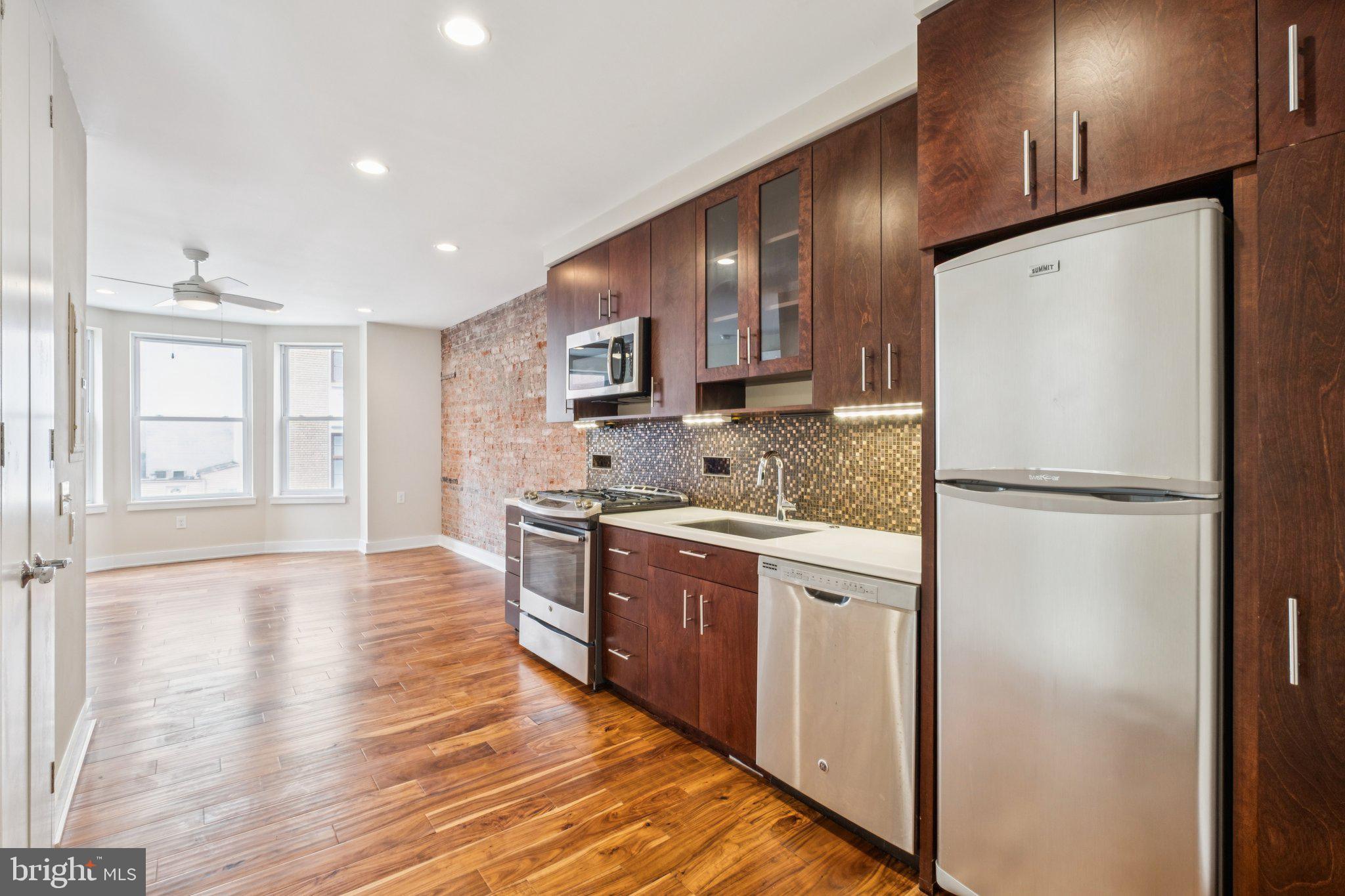131 South 13th Street, Unit 3F Philadelphia, PA 19107 - Photo 1 of 14 a kitchen with a refrigerator a stove top oven a sink and dishwasher with wooden floor