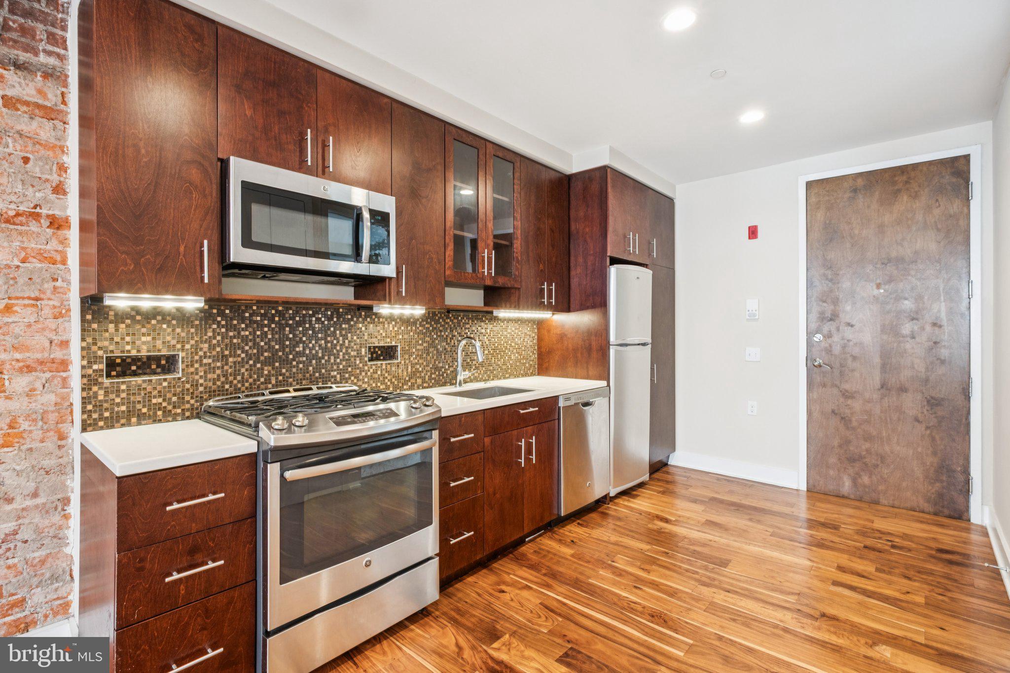 131 South 13th Street, Unit 3F Philadelphia, PA 19107 - Photo 6 of 14 a kitchen with stainless steel appliances granite countertop a stove a refrigerator and a microwave
