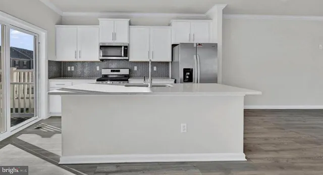 a kitchen with stainless steel appliances a refrigerator a stove a sink and white cabinets