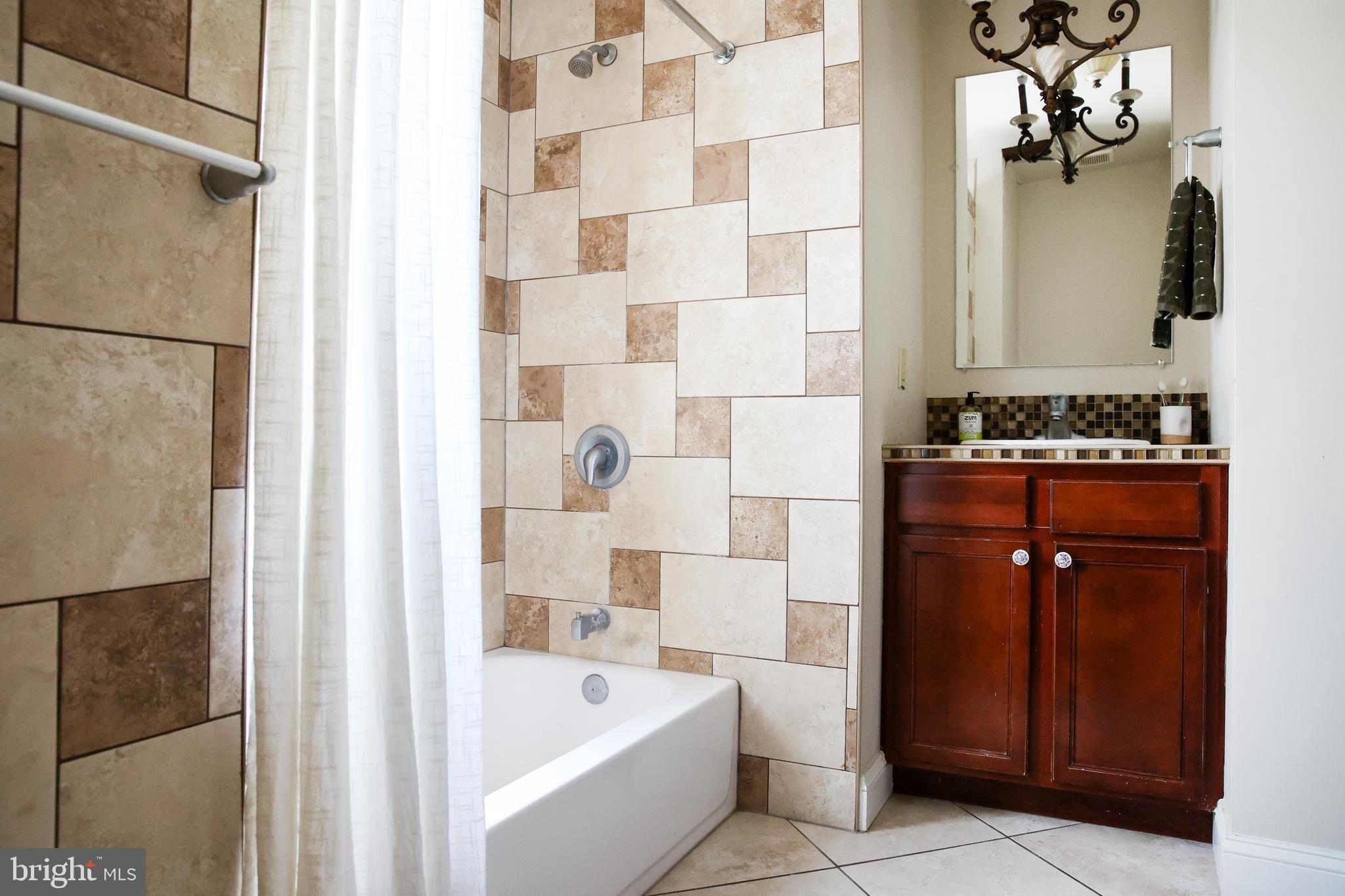 2226 Eutaw Place, Unit 3 Baltimore, MD 21217 - Photo 9 of 15 a bathroom with a bathtub sink vanity and mirror
