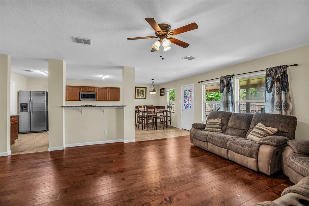 5718 Green Ivy Road Denton, TX 76210 - Photo 14 of 37 Spacious living area featuring wood-finish flooring, a ceiling fan with integrated lighting, and multiple windows