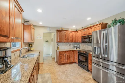 a kitchen with stainless steel appliances granite countertop a refrigerator a stove and a sink