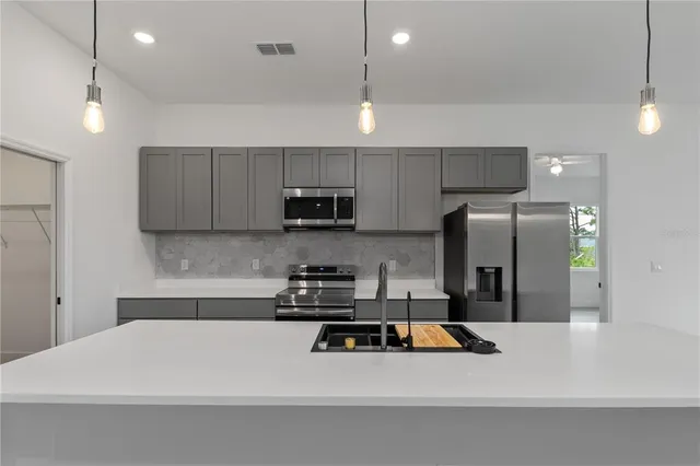 a kitchen with stainless steel appliances a refrigerator a sink a stove a microwave and white cabinets