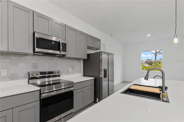 a kitchen with stainless steel appliances a stove a microwave a sink a refrigerator and cabinets