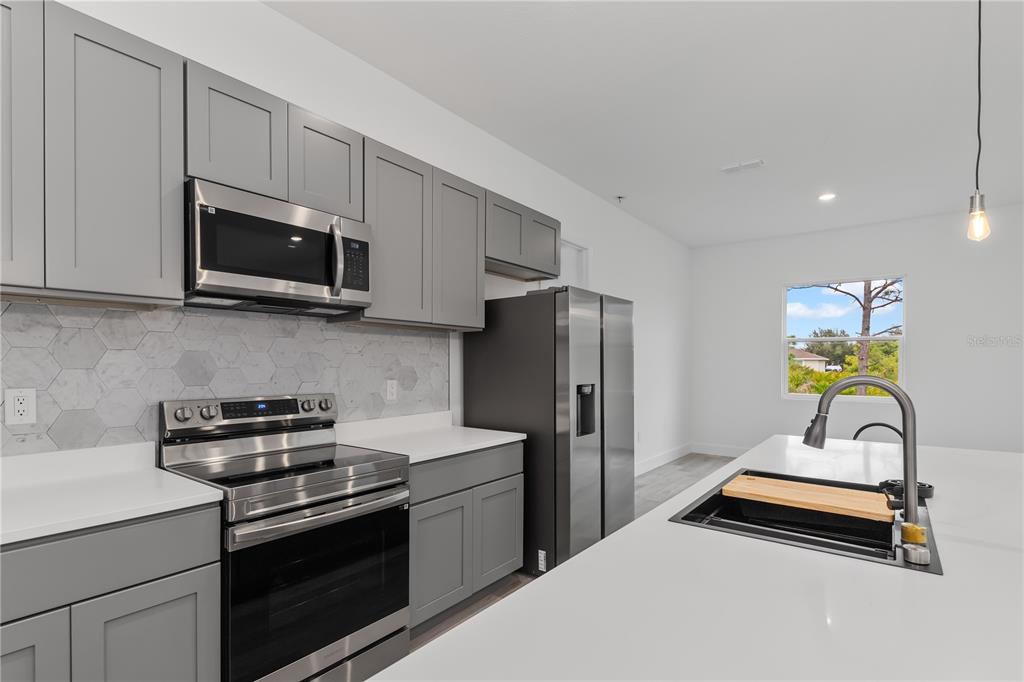 13514 Keystone Boulevard Port Charlotte, FL 33981 - Photo 12 of 42 a kitchen with stainless steel appliances a stove a microwave a sink a refrigerator and cabinets