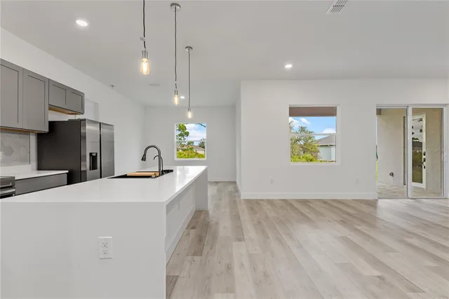 a view of a kitchen with a sink wooden cabinets and entryway