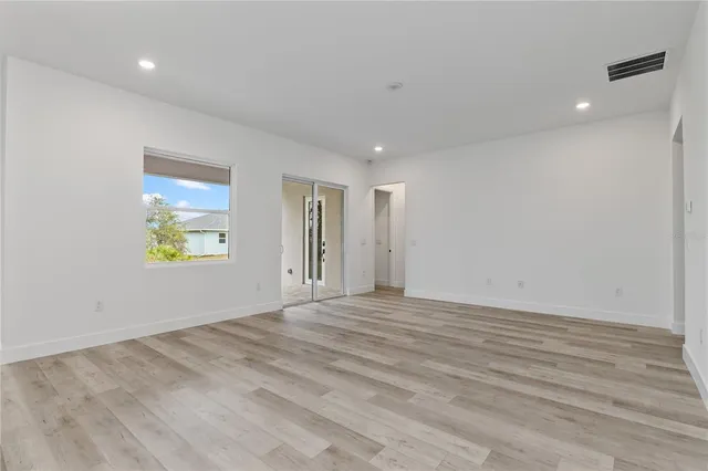 a view of an empty room with window and wooden floor