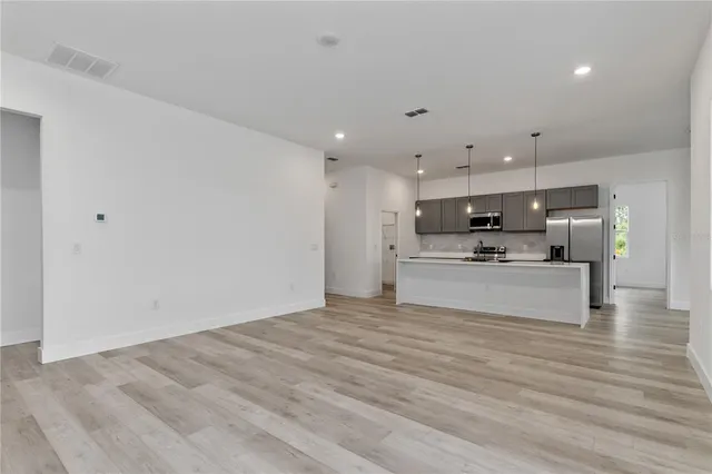a view of kitchen with kitchen island stainless steel appliances cabinets and wooden floor