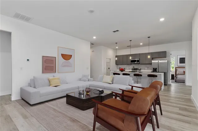 a living room with furniture kitchen view and a wooden floor