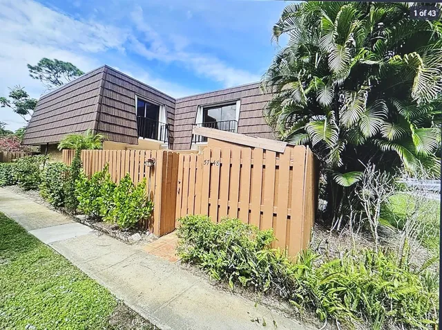 a view of a house with potted plants and a large tree