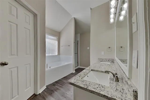 a bathroom with a granite countertop tub sink and mirror
