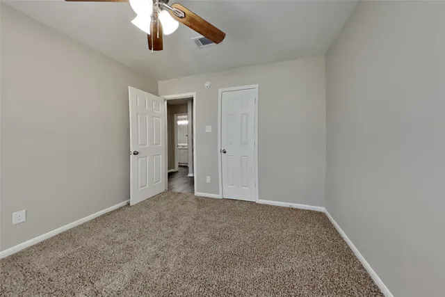 an empty room with a chandelier fan and windows