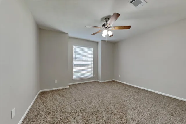 an empty room with windows and fan
