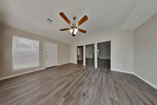 an empty room with wooden floor and windows