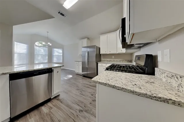 a kitchen with stainless steel appliances granite countertop a sink a stove and a wooden floors