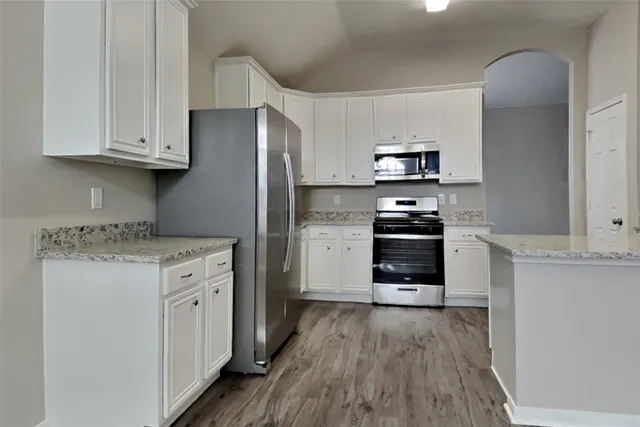 a kitchen with granite countertop a stove and a refrigerator