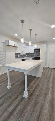 a large kitchen with cabinets wooden floor and stainless steel appliances