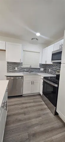 a white kitchen with granite countertop a stove top oven sink and cabinets