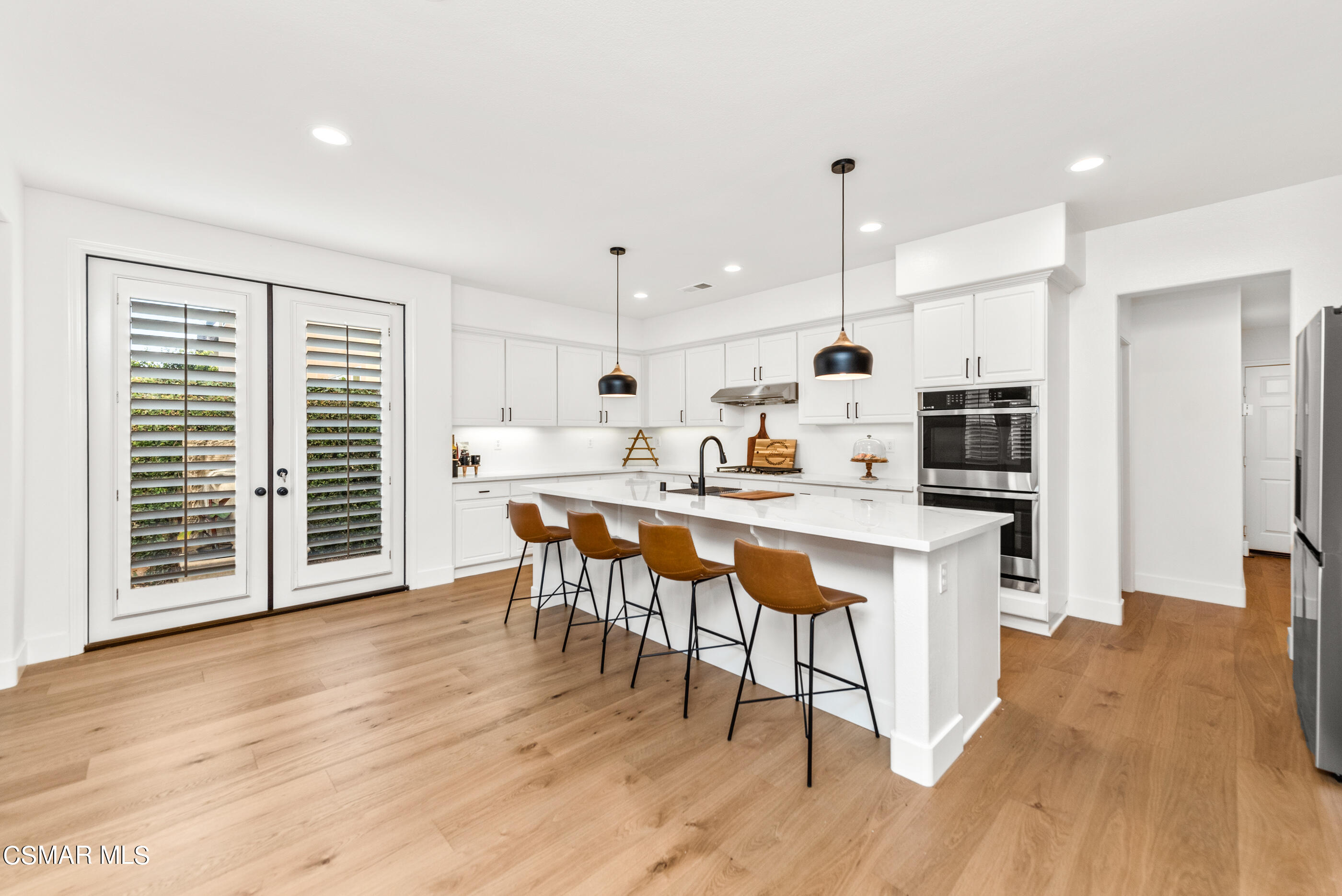 5984 Piuma Court Simi Valley, CA 93063 - Photo 21 of 70 a open kitchen with stainless steel appliances granite countertop a stove a refrigerator a kitchen island a dining table and chairs with wooden floor