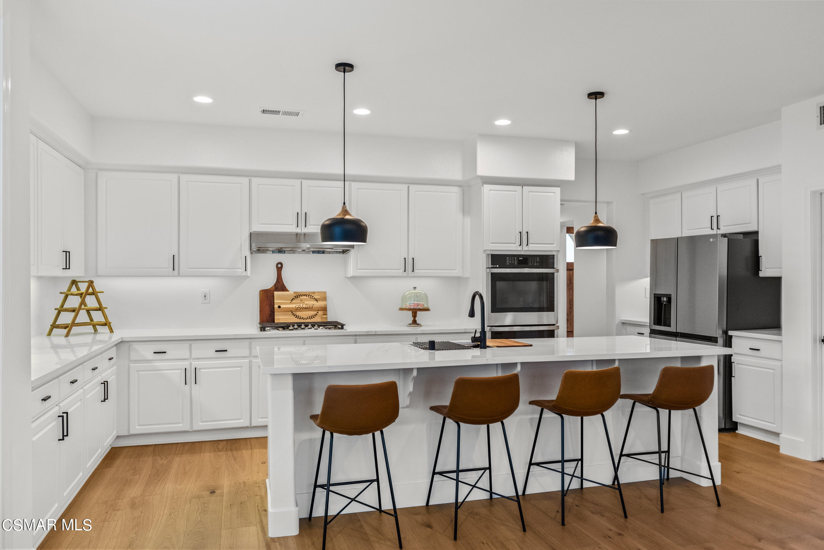 5984 Piuma Court Simi Valley, CA 93063 - Photo 28 of 70 a kitchen with stainless steel appliances kitchen island granite countertop a stove a refrigerator a sink a stove with white cabinets and wooden floor