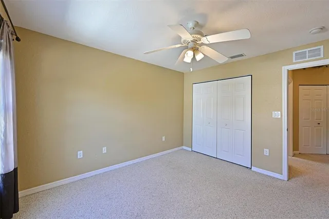 an empty room with a ceiling fan and a window