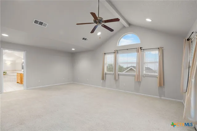 an empty room with chandelier fan and windows
