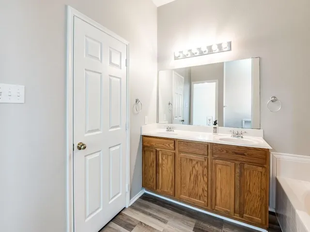 a spacious bathroom with a double vanity sink a mirror and a bathtub