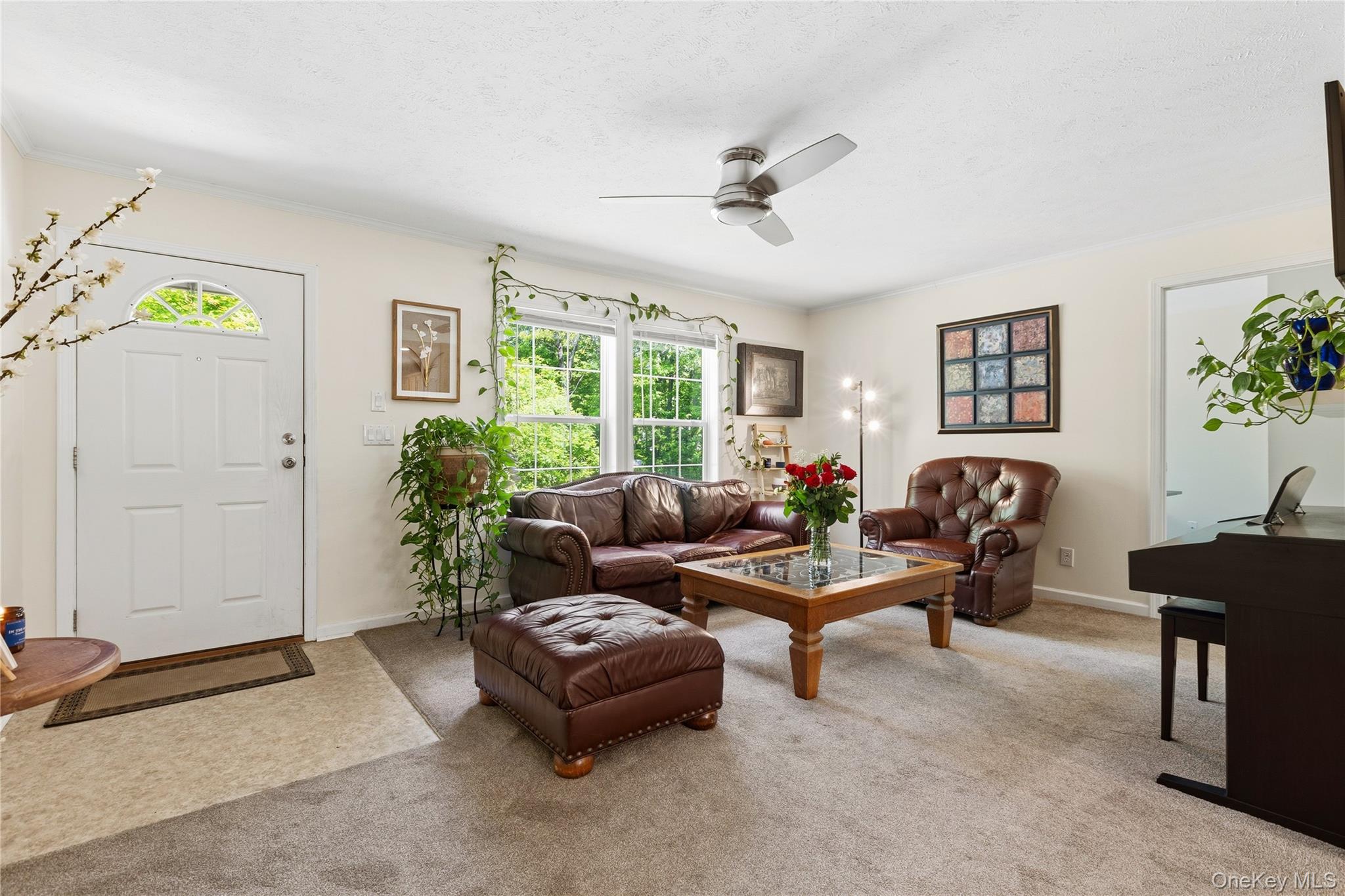 239-241 Fosler Road Highland, NY 12528 - Photo 31 of 42 Light-filled living area featuring a white paneled entry door with an arched transom window, large picture windows, a ceiling fan with integrated lighting, and neutral wall tones