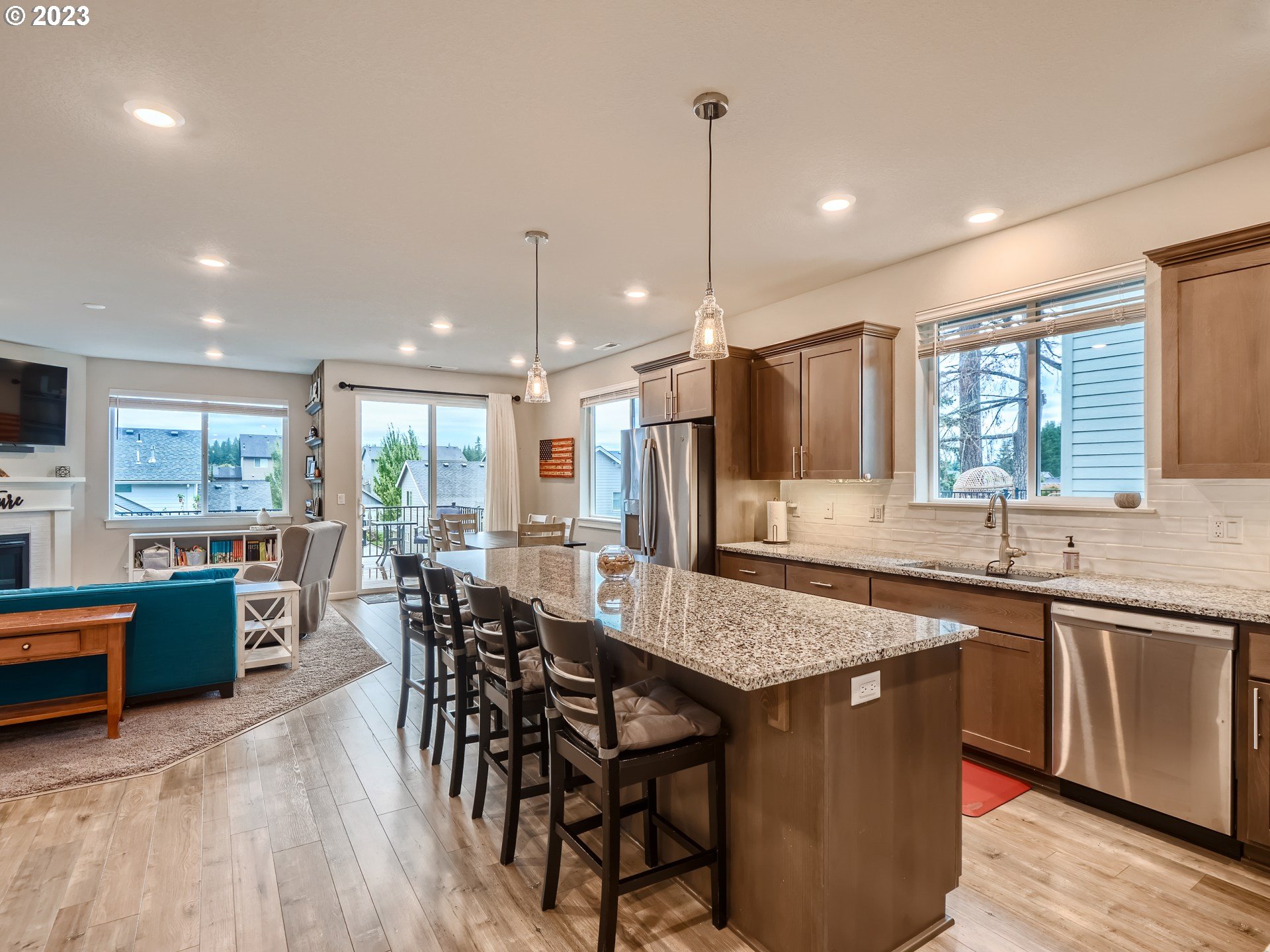 38439 Maple Street Sandy, OR 97055 - Photo 4 of 34 an open kitchen with granite countertop a stove a sink a dining table and chairs with wooden floor