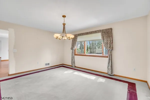 a view of an empty room with chandelier and a window