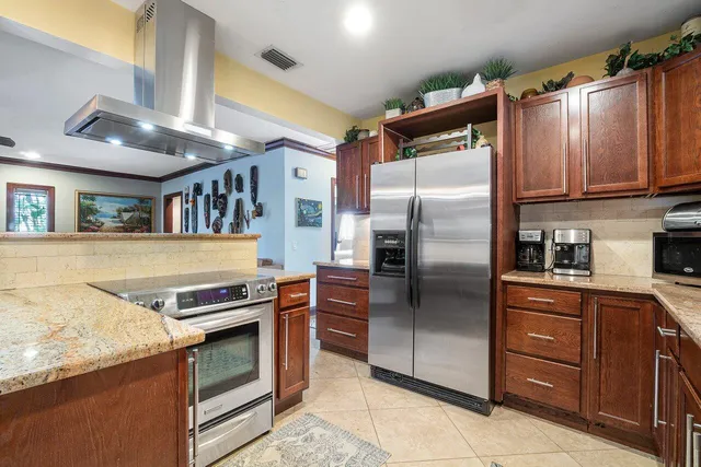 a kitchen with stainless steel appliances granite countertop a stove and a chandelier