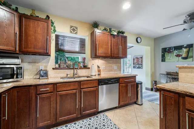 a kitchen with stainless steel appliances kitchen island granite countertop a sink a stove a refrigerator cabinets and chairs