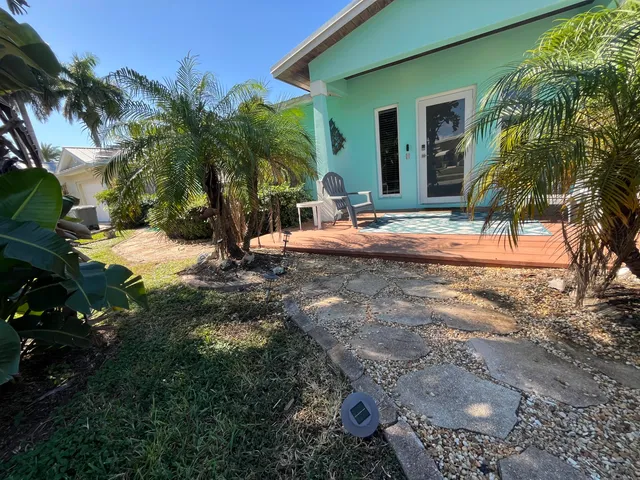 a view of the house with a yard and palm trees