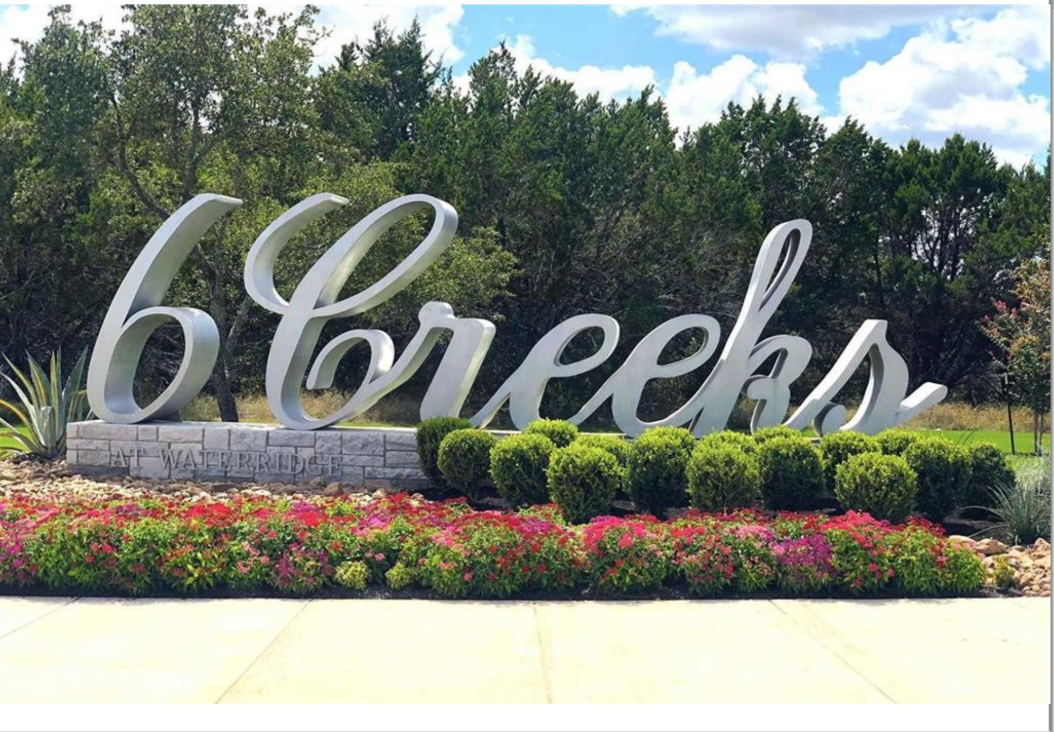 294 Kimble Creek Loop Kyle, TX 78640 - Photo 33 of 40 Welcoming entrance to a community, bordered by manicured landscaping and vibrant floral beds.