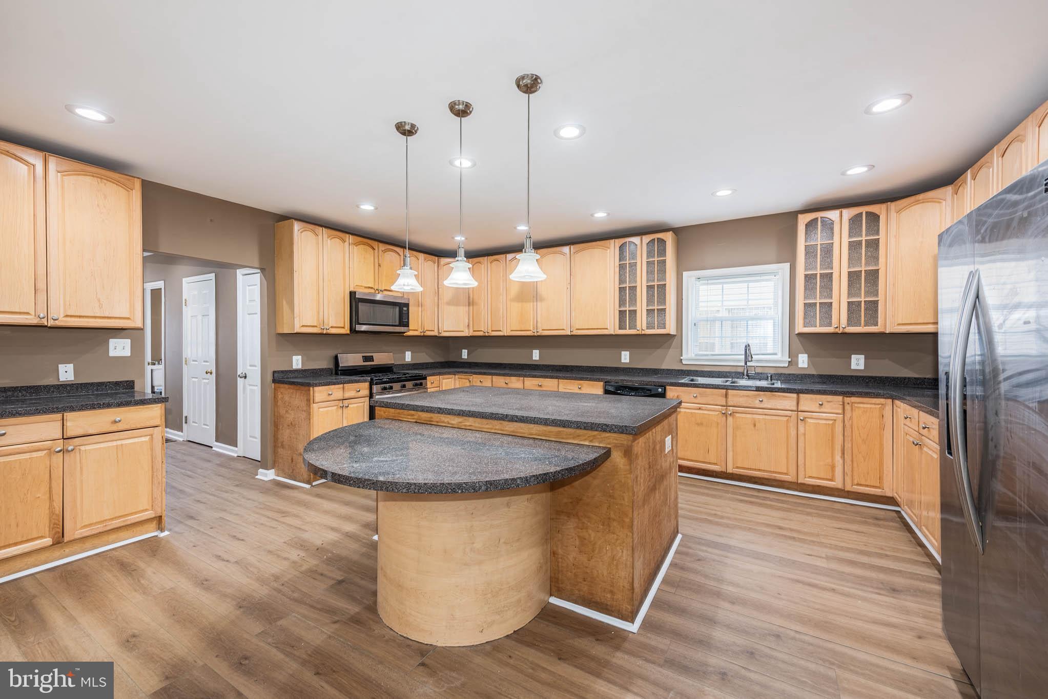 4021 Barrington Road Baltimore, MD 21207 - Photo 9 of 50 a kitchen with stainless steel appliances granite countertop a sink a stove a refrigerator and island with wooden floor