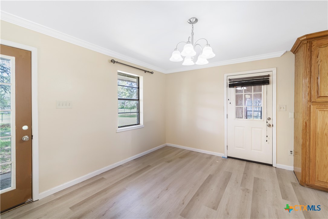 1033 Farm To Market 1351 Goliad, TX 77963 - Photo 13 of 34 an empty room with wooden floor chandelier and windows