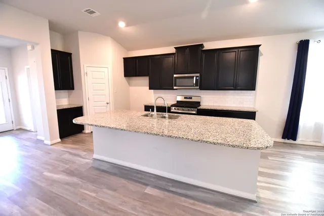 a kitchen with stainless steel appliances kitchen island granite countertop a refrigerator and a sink