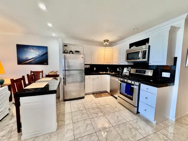 a kitchen with stainless steel appliances kitchen island granite countertop a refrigerator and a stove top oven