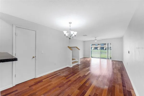a view of a room with wooden floor and a ceiling fan
