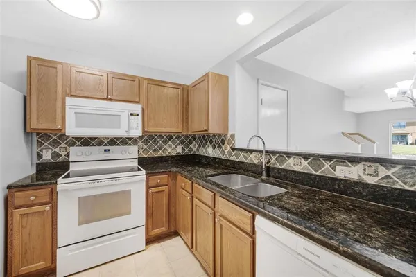 a kitchen with granite countertop a sink stove top oven and cabinets