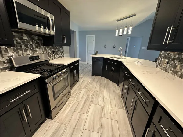 a kitchen with granite countertop a sink stove and cabinets