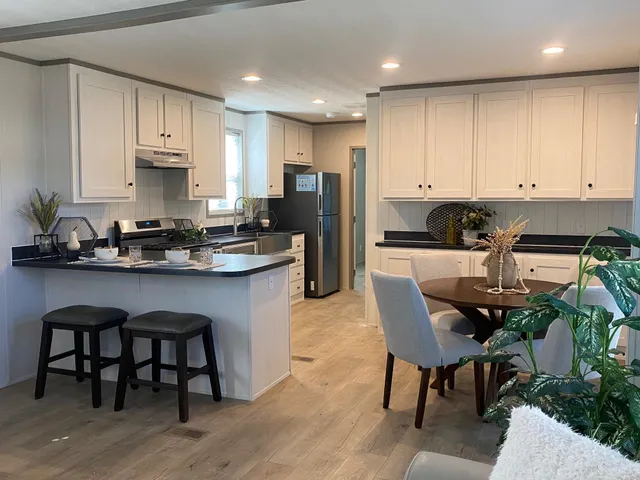 a kitchen with stainless steel appliances granite countertop a table chairs sink refrigerator and cabinets