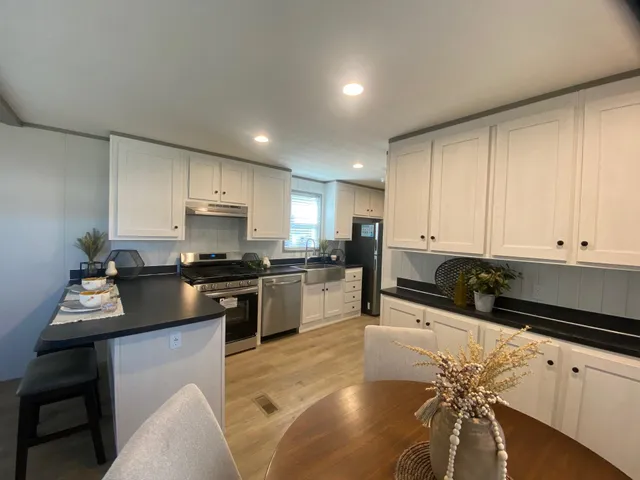 a kitchen with granite countertop a sink a stove top oven a counter space and cabinets